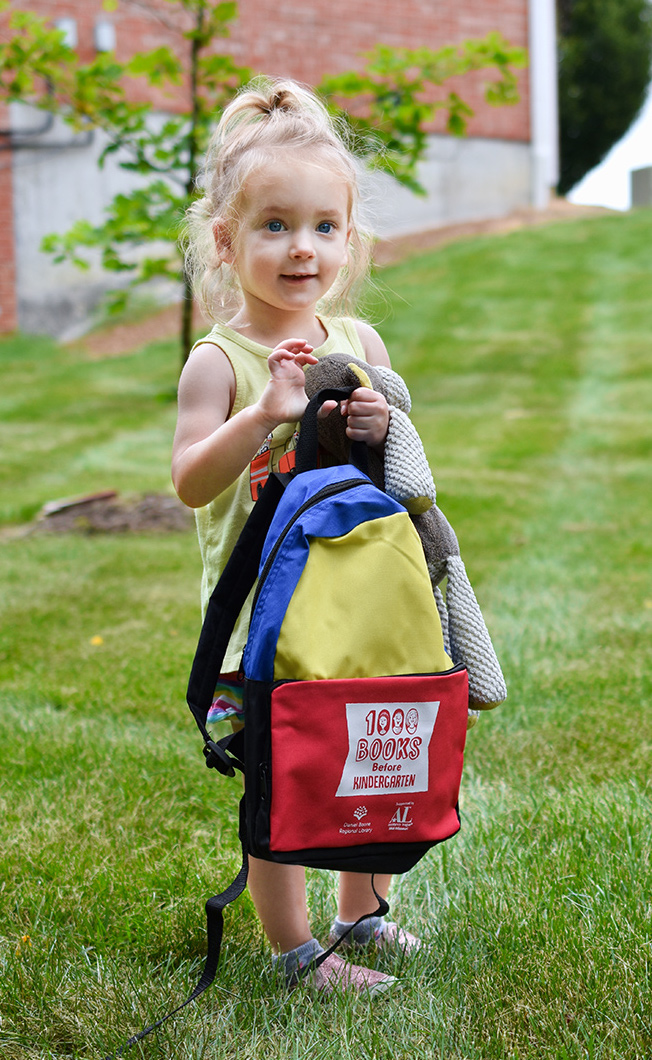 girl holding the Daniel Boone Regional Library's 1,000 Books Before Kindergarten backpack