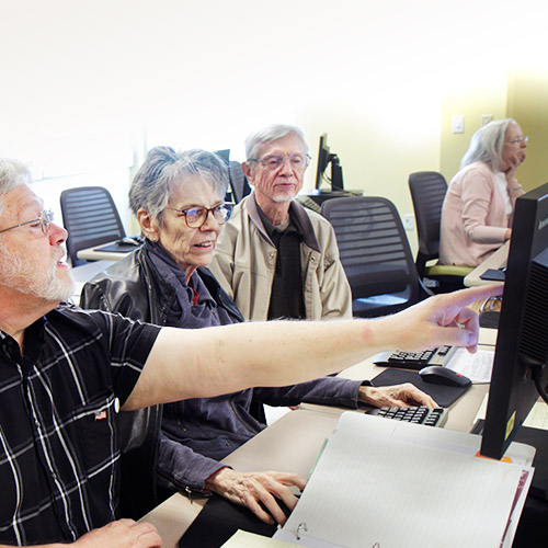 patrons get computer training from a library staff member