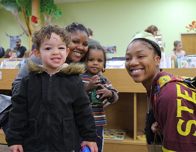 Parents and young children smile in the children's area of the Holts Summit Public Library