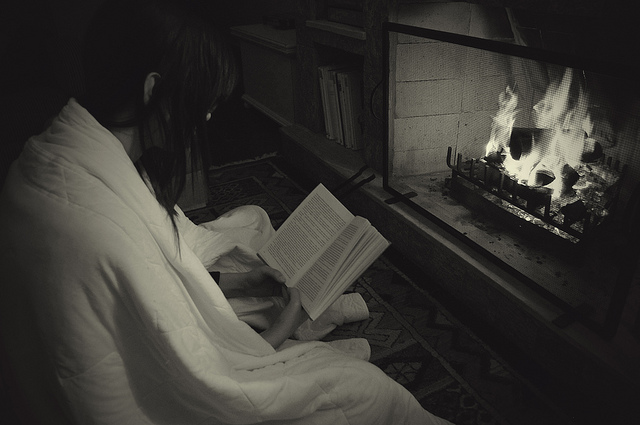 photo of girl reading in front of fireplace