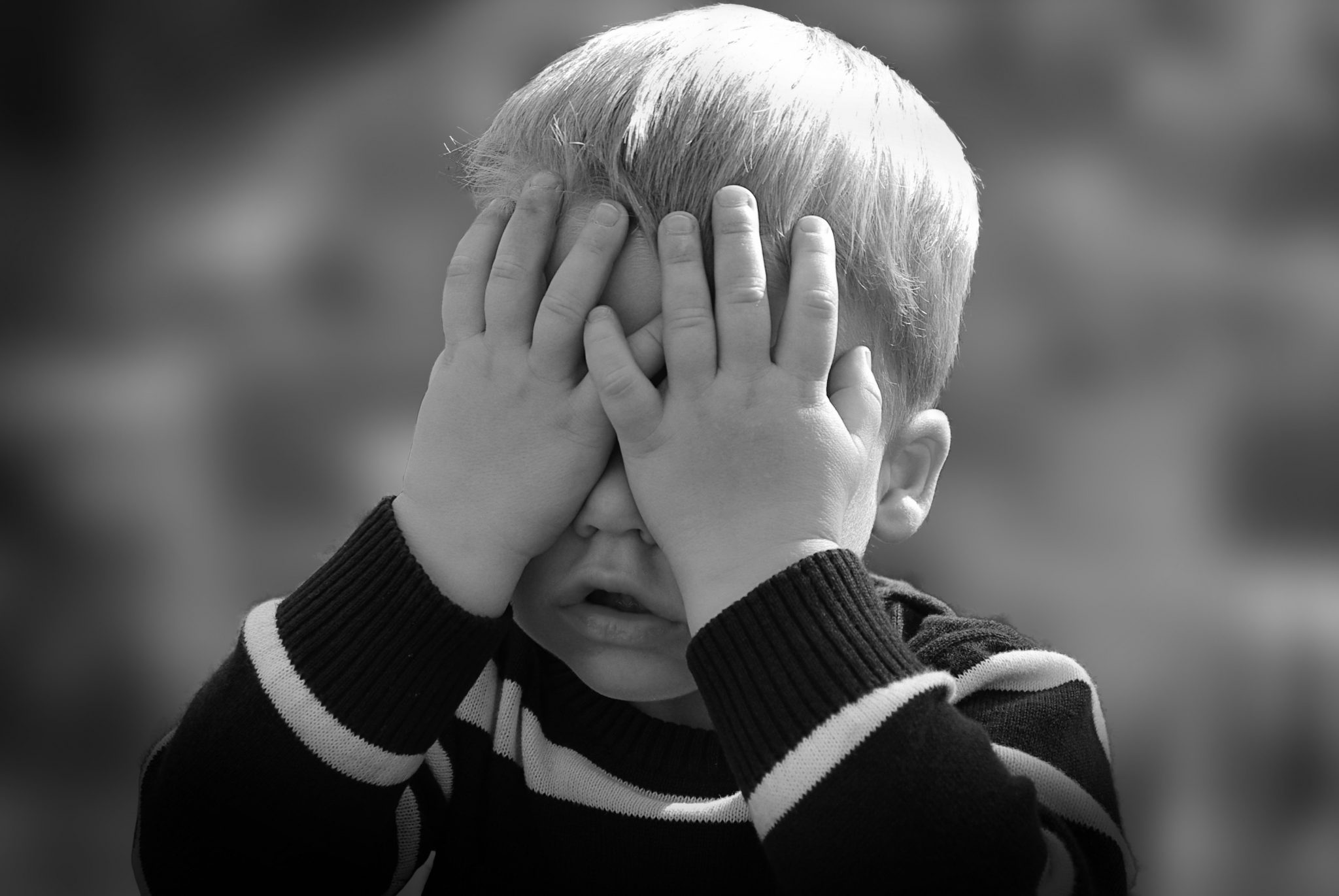 Photograph of a young boy covering his face