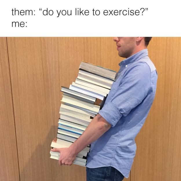 photo of man holding a large pike of books