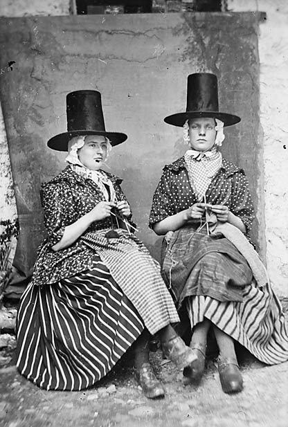 two women in traditional dress knitting