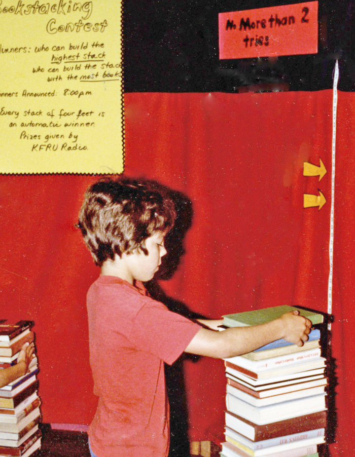 Boy trying to stack 25 books for the 25th anniversary of the Columbia Public Library.