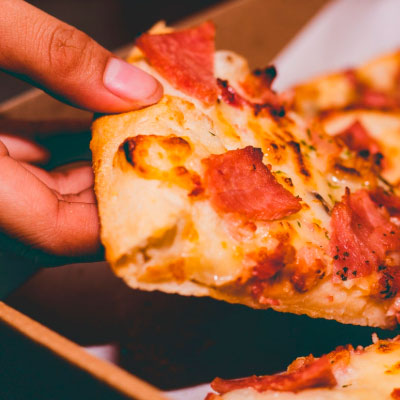 close up of a hand holding a slice pizza