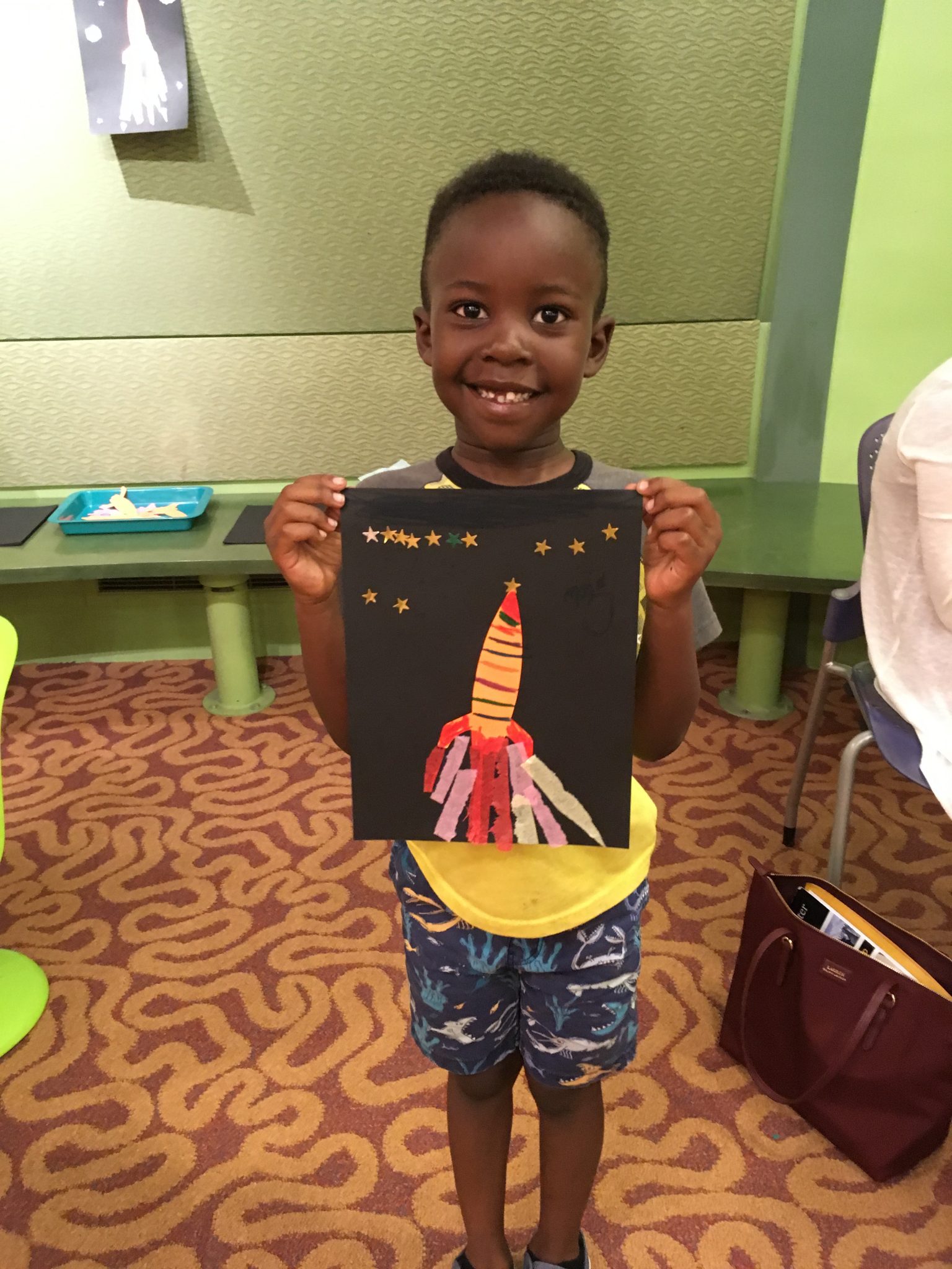 child holds up finished rocket art