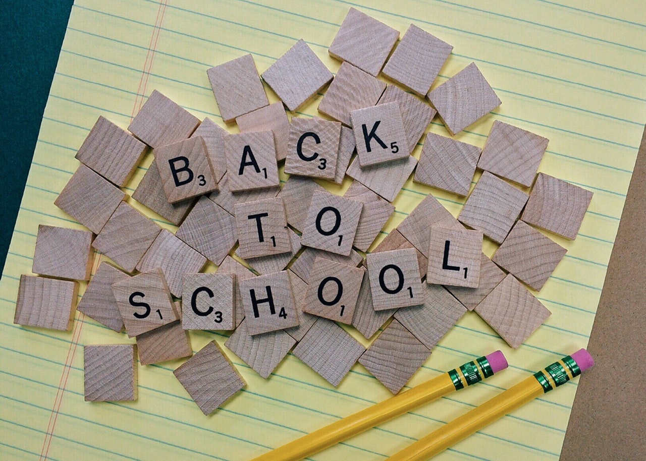 yellow legal pad with pencils and scrabble tiles on top, tiles spelling "back to school"