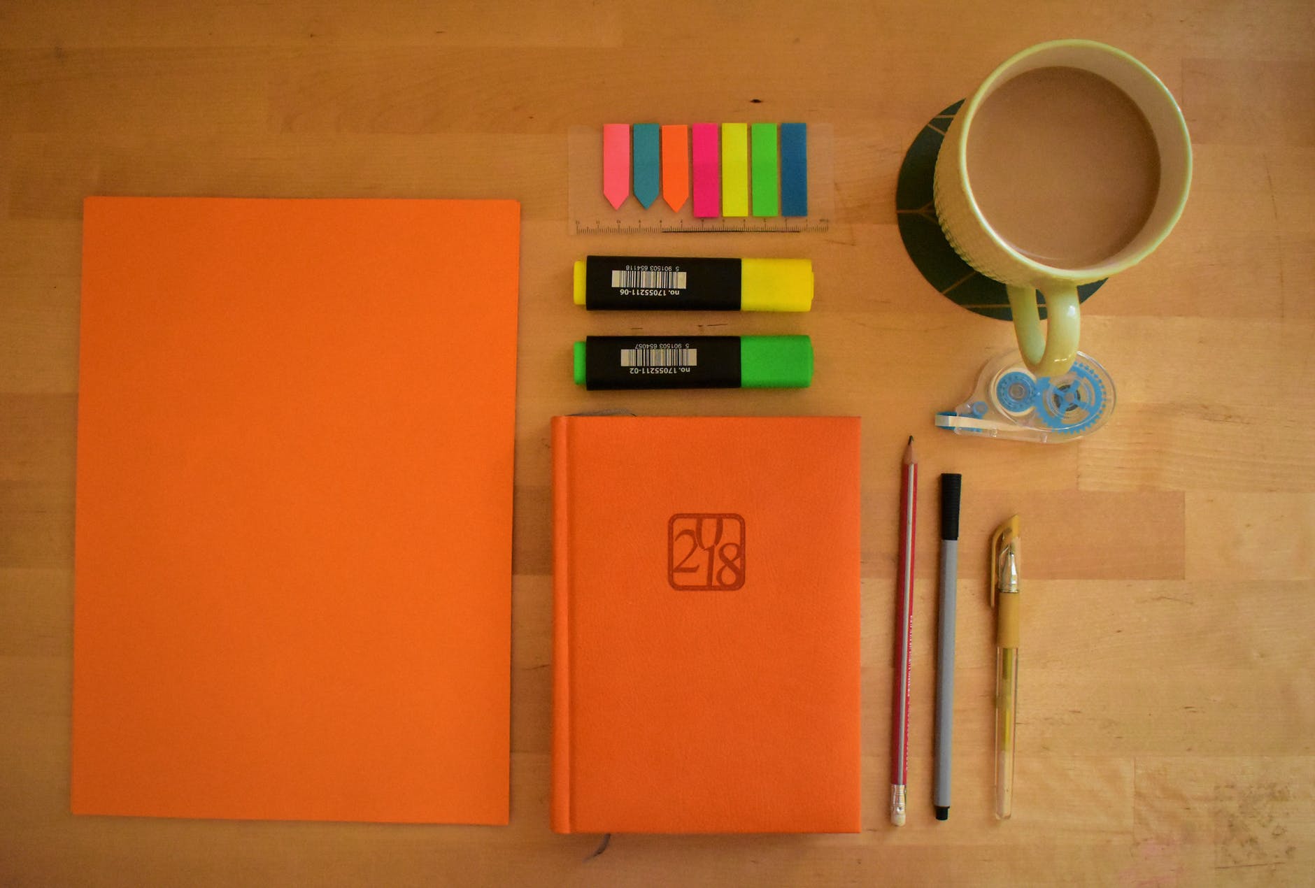 orange jounral on table with pens and coffee