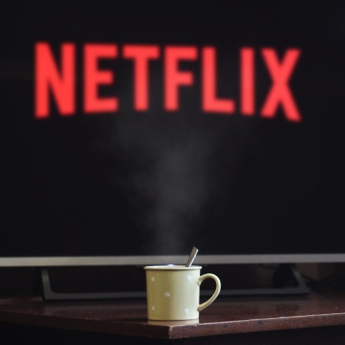 mug of warm beverage posed in front of screen with "Netflix" logo on it
