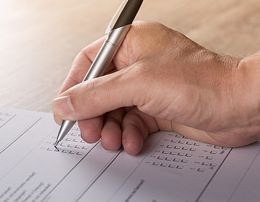 image of person's hand filling out a paper form with a pen