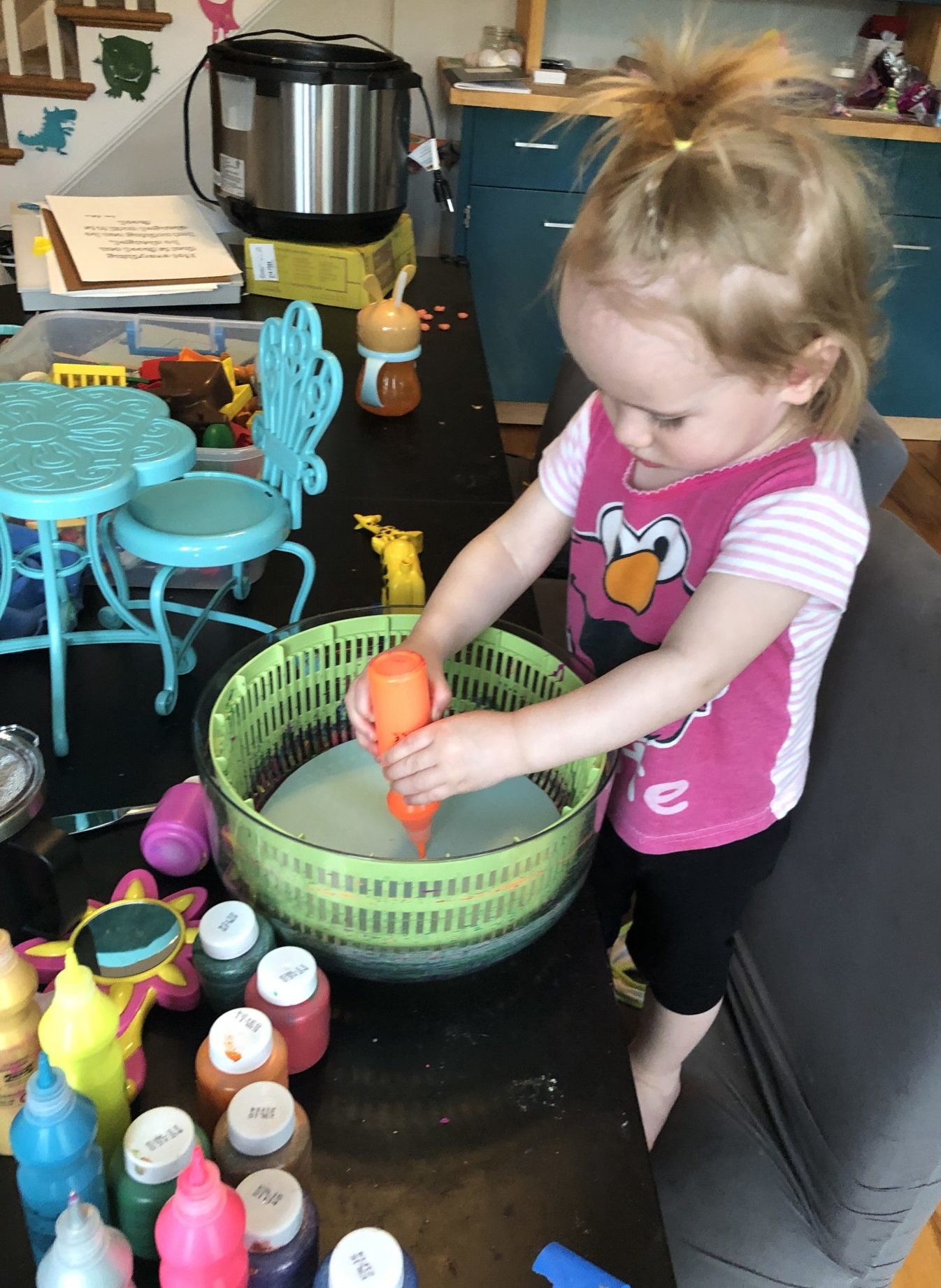 child squeezing paint into salad spinner