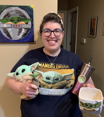 Woman holding many Baby Yoda items.