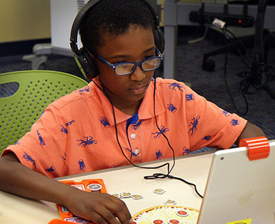 child with headphones at computer