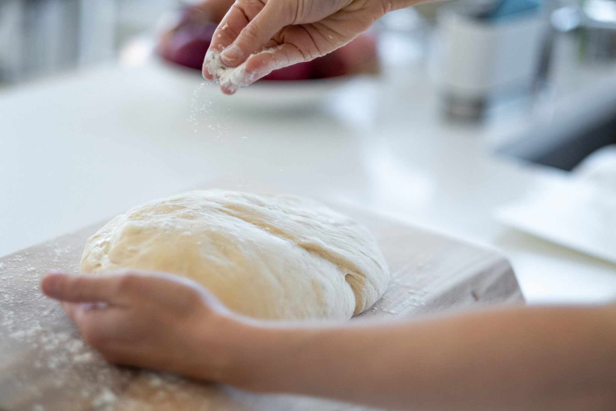 bread dough being sprinkled with flour