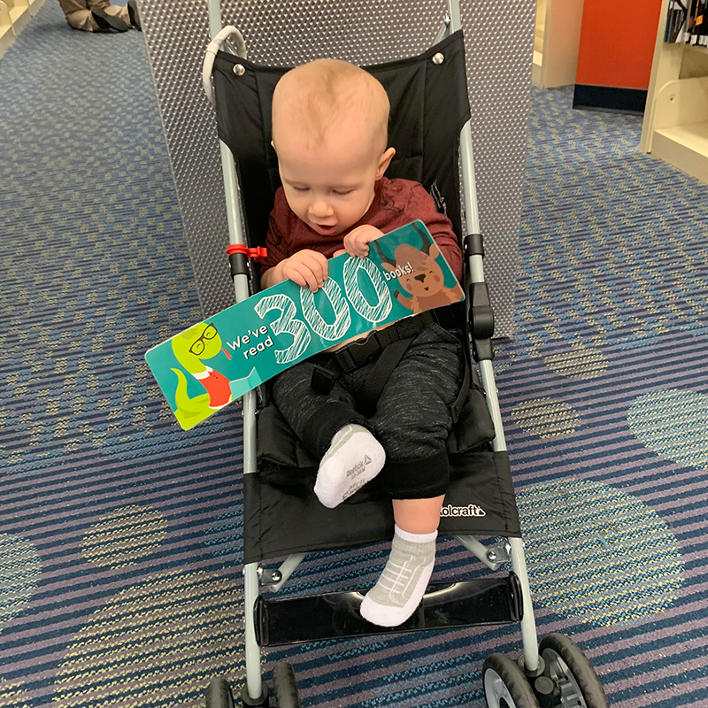 A participant in DBRL's 1000 Books Before Kindergarten program holds up a sign reading "we've read 300 books"