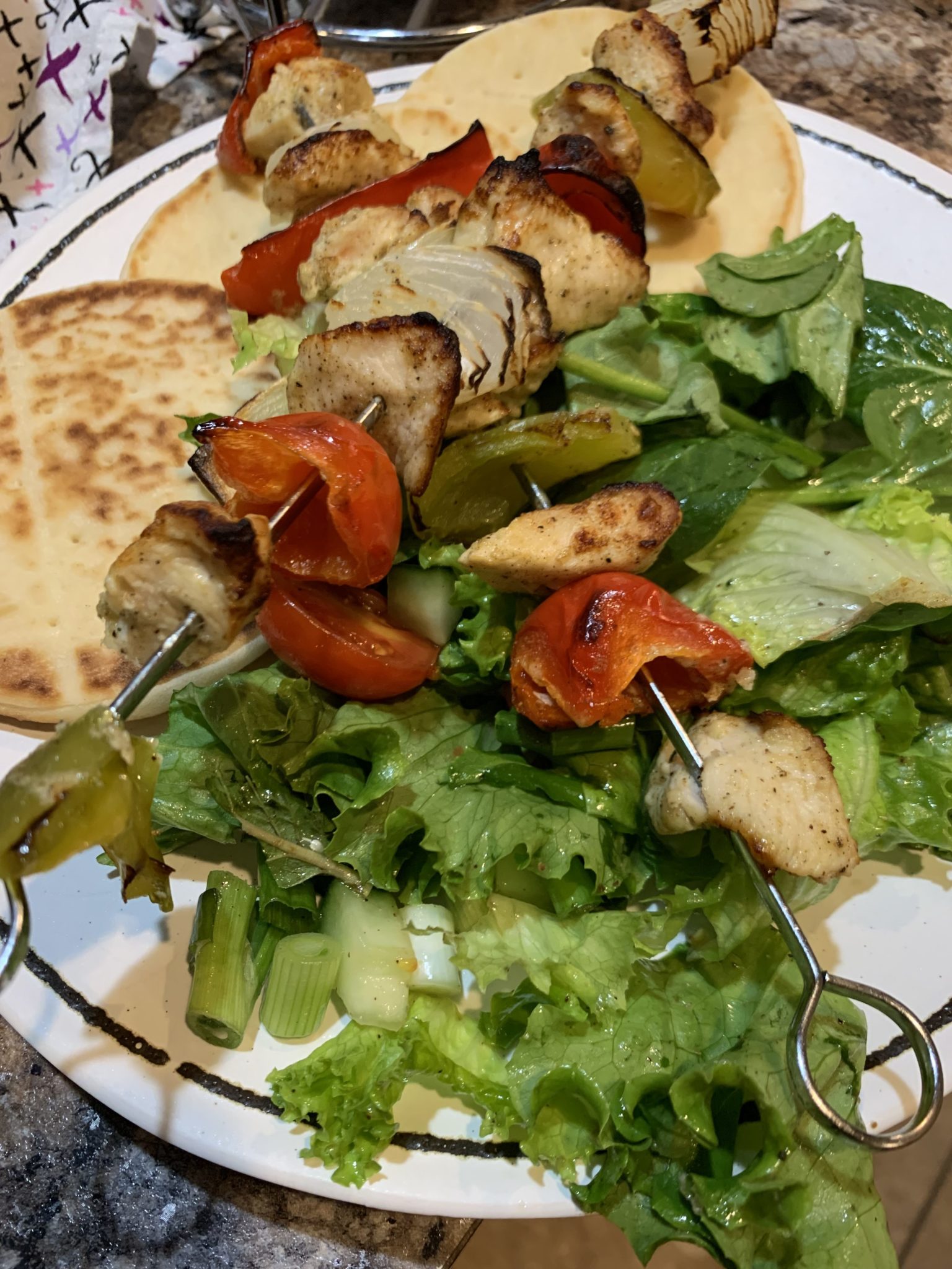 Picture of a plate with salad, kebabs and flat bread.