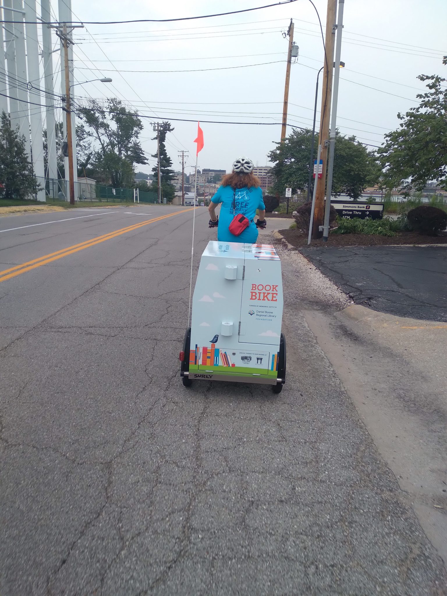 woman riding a book bike down a public street