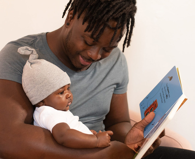 a man reading a board book to his baby