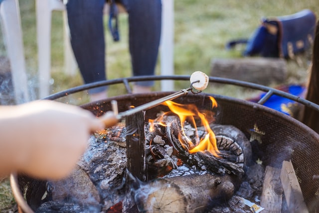 roasting marshmallow on a stick over a small campfire