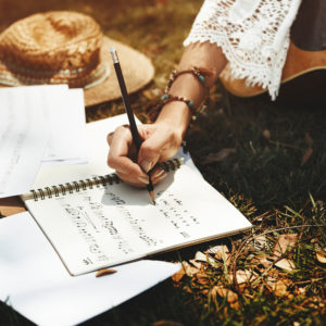 Woman writing music on the grass