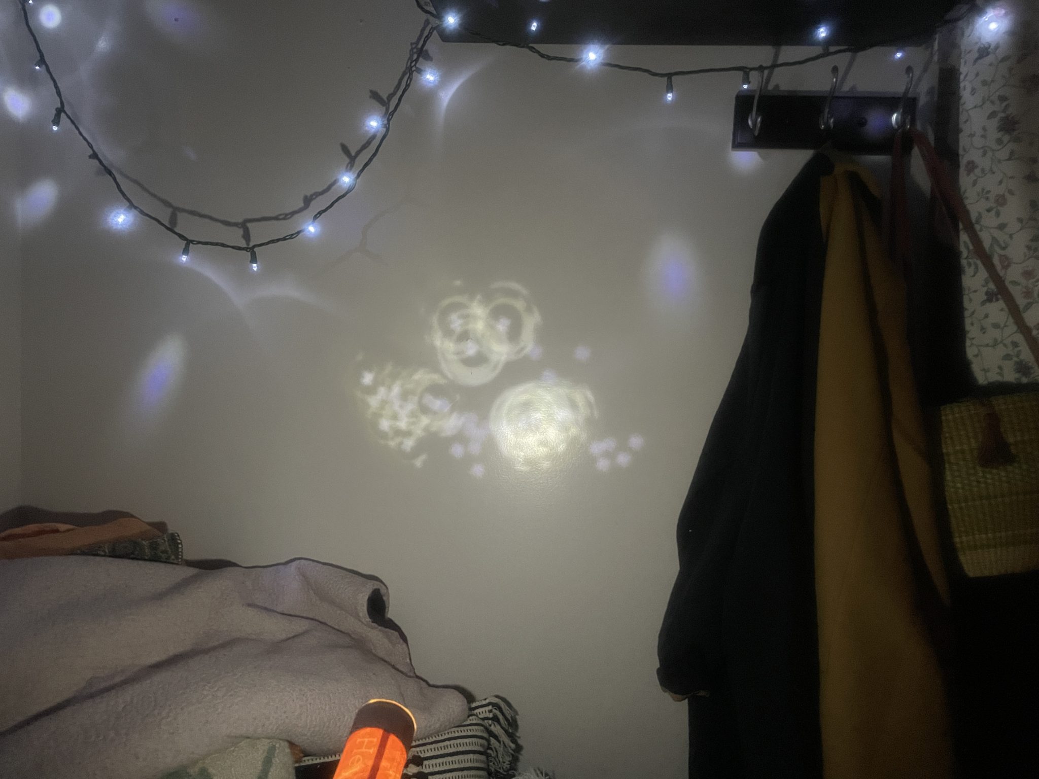 Photo of an illuminated star-map experiencing the effects of diffraction. Instead of the flashlight shining through the map and making clear pinpricks of light on the wall, the light appears warped and rippling.