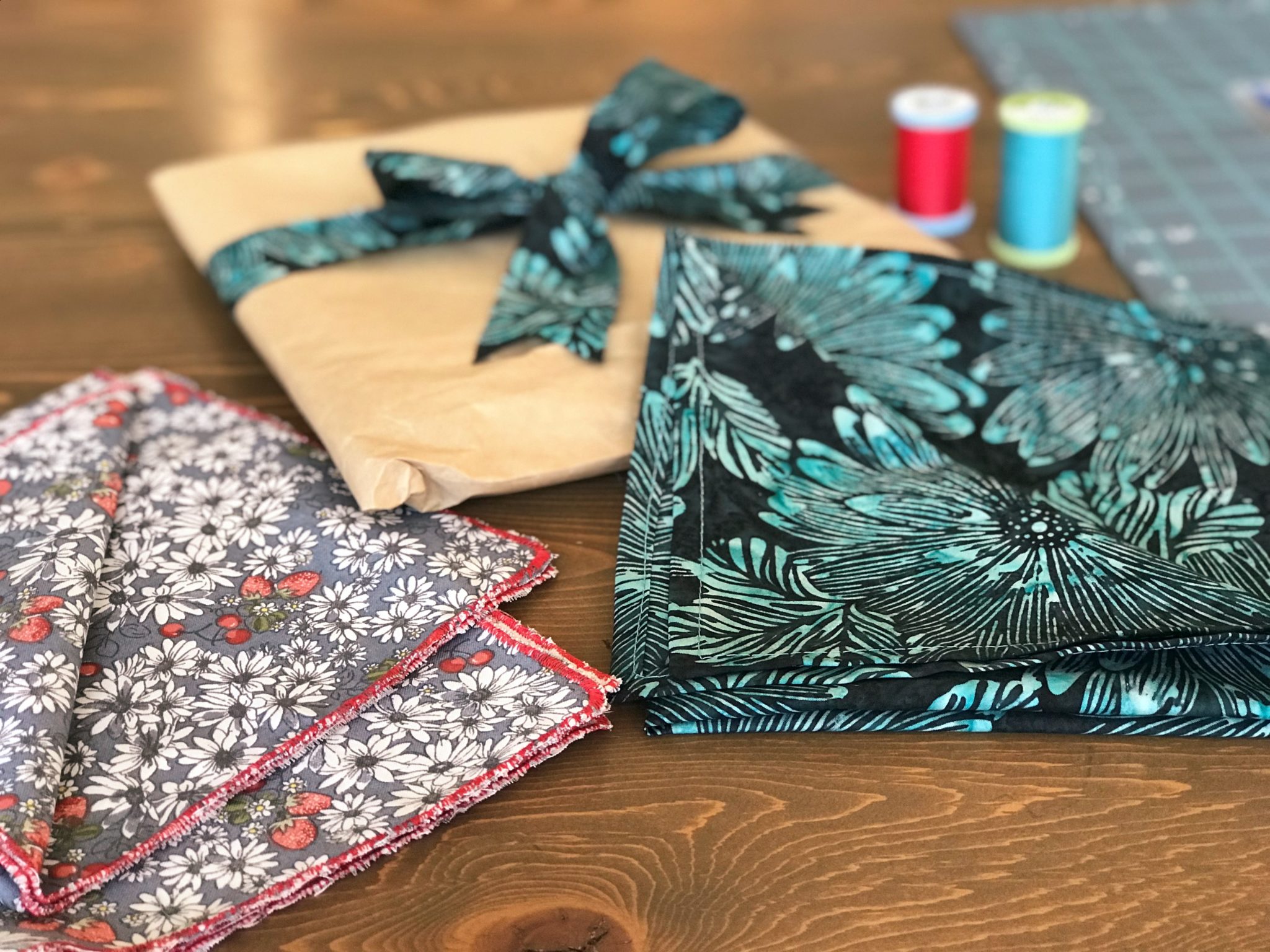 Two sets of cloth napkins and a wrapped present sit on a table