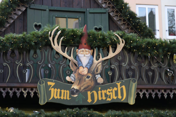 German style gnome on a stag's head with the text "zum nirsch" below them