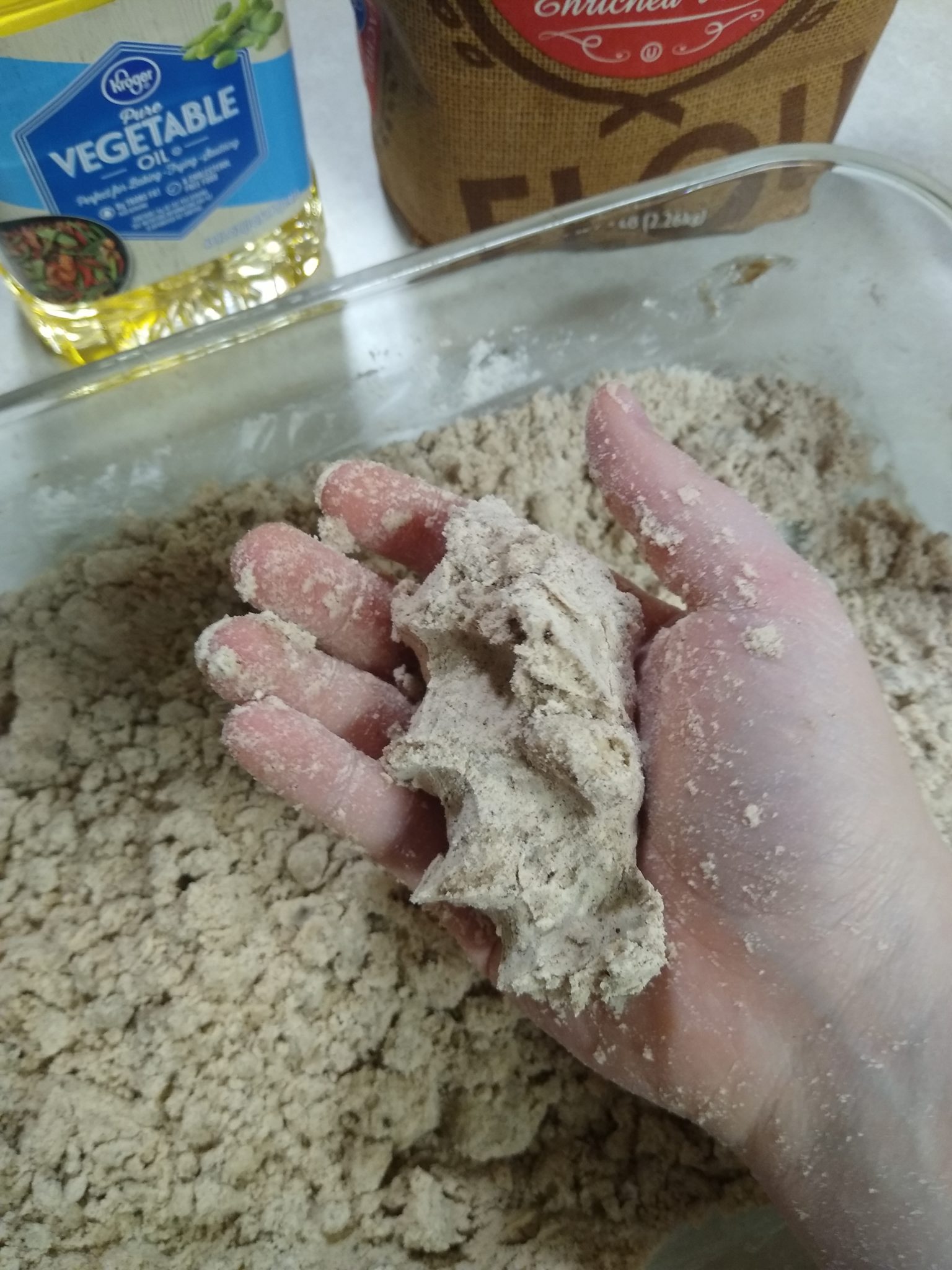 Demonstrating the ideal texture of the dough; the dough remains crumbly but can be easily compressed down by hand.