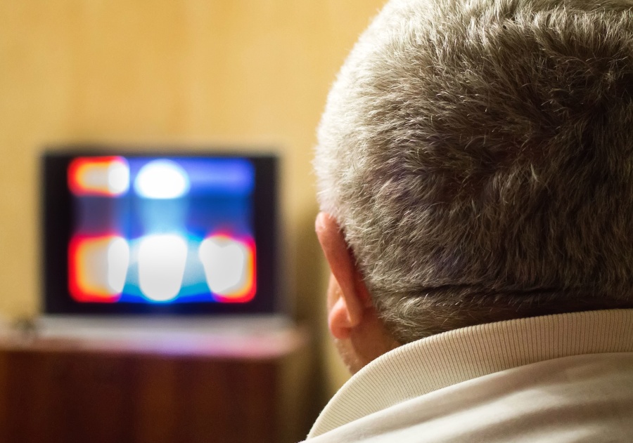 person with short gray hair watching a television