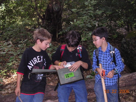 three kids open a geocache in the woods