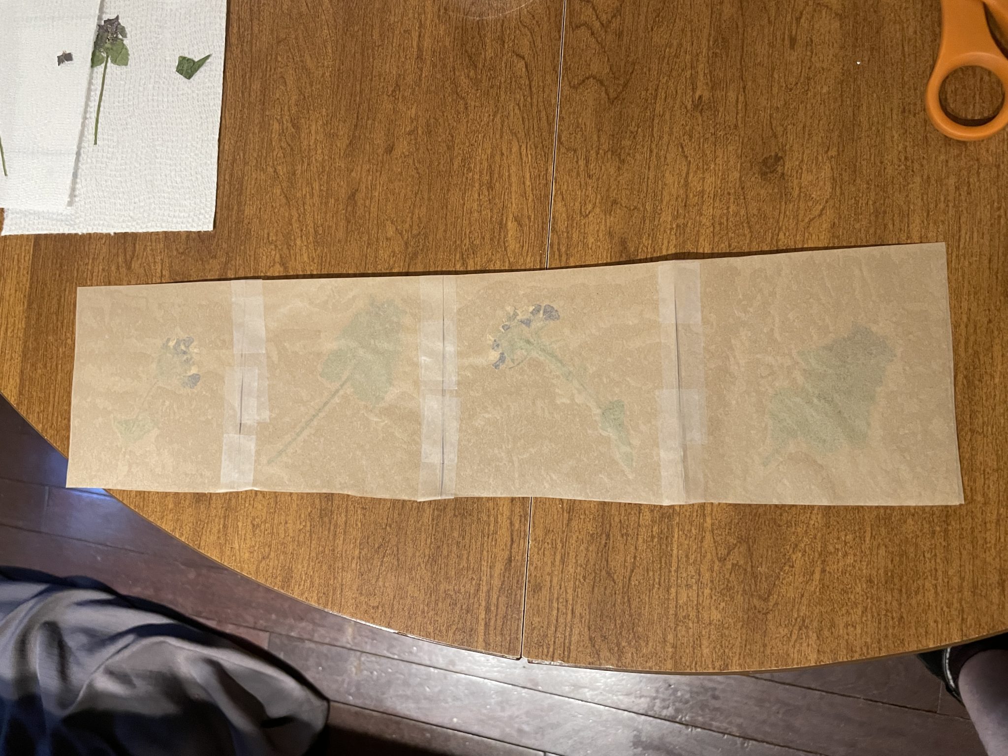 Photo of four squares of fused waxed paper laid out on a table and taped together.