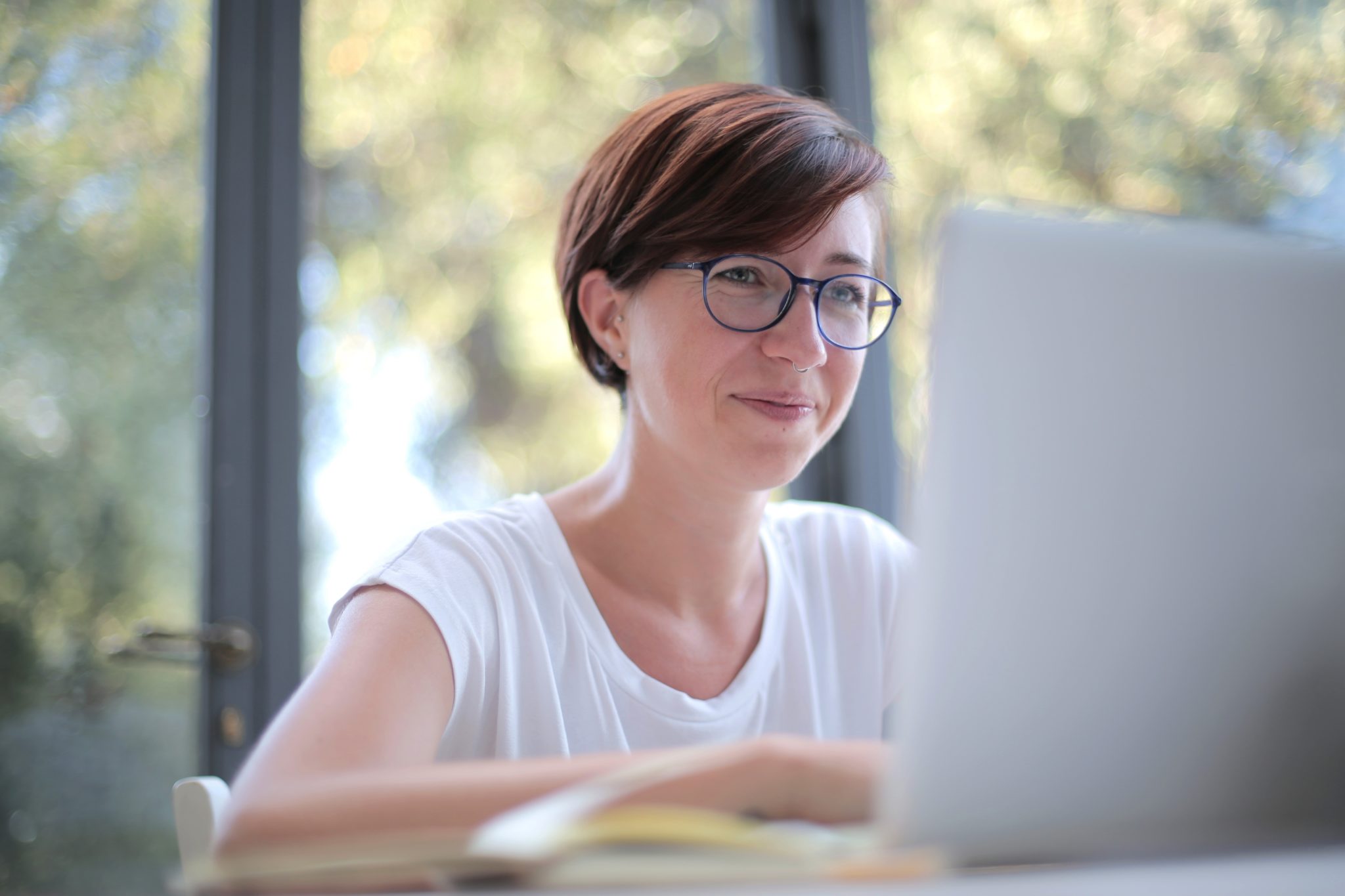 Image of a white woman in a white shirt working on a laptop
