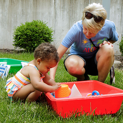 a woman helping a child play with colorful objects of various shapes