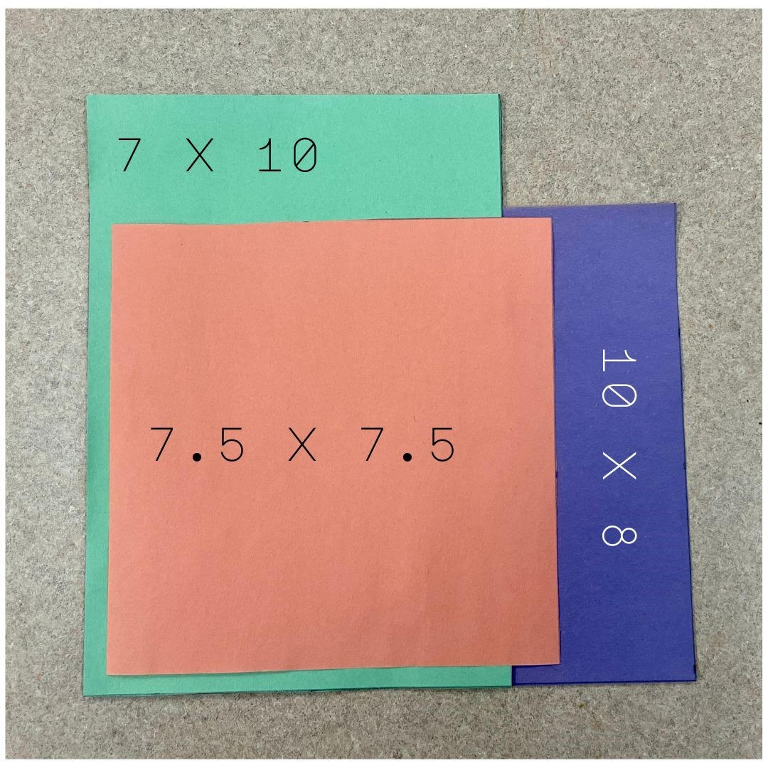 Two rectangles and one square piece of construction paper layered on top of one another to illustrate the three standard sizes found in children's picture book publishing. The bottom-most purple piece of construction paper measures 10 x 8 inches, the middle green piece of construction paper measures 7 x 10 inches, and the top-most orange piece of construction paper measures 7.5 x 7.5 inches. 