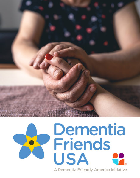 A photo of one person clasping another person's hand across a table, plus the Dementia Friends USA logo at the bottom