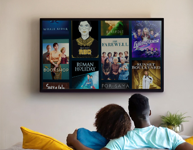 a couple sits on a couch facing a TV browsing Kanopy movies