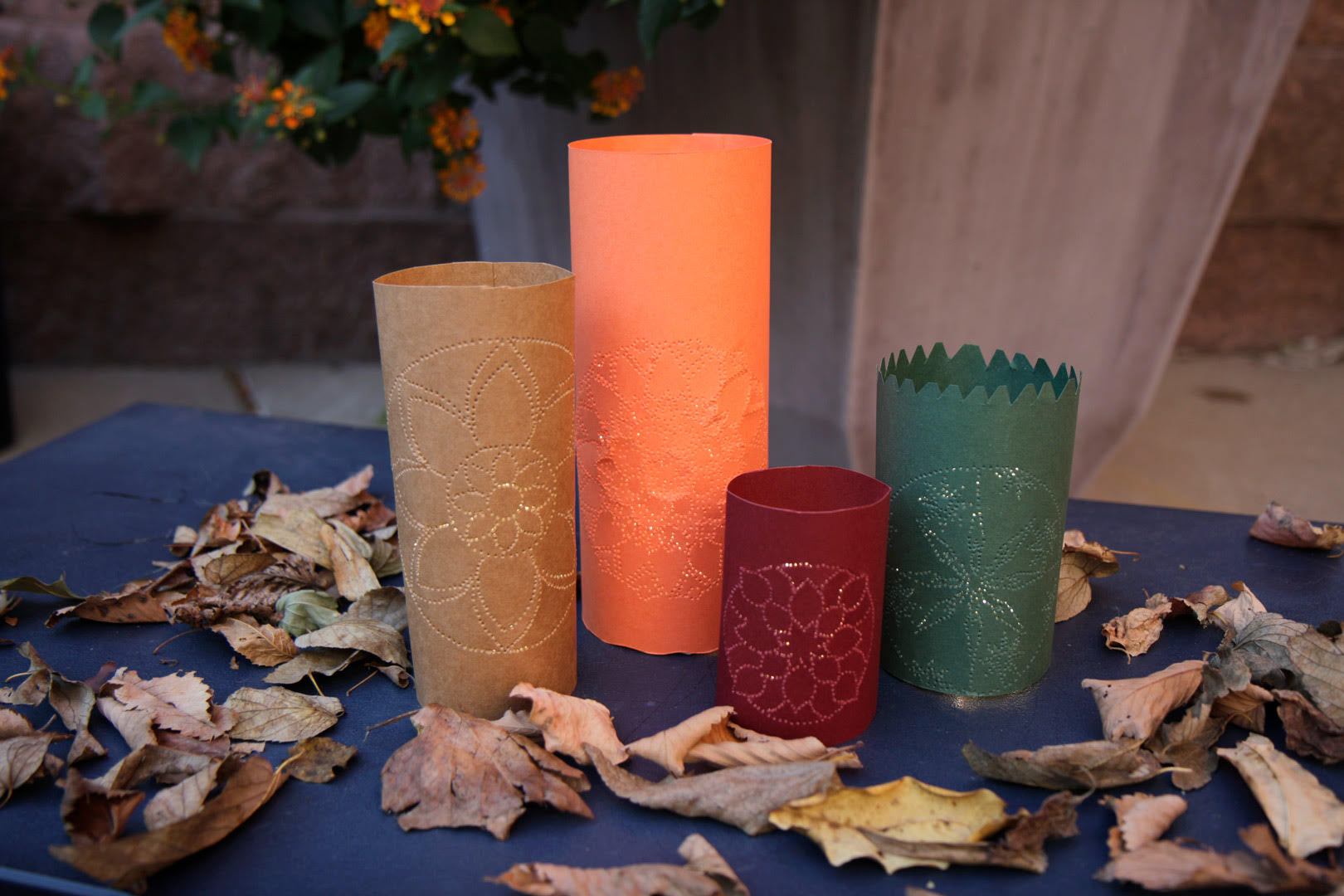 paper luminarias in fall colors with dried leaves around them