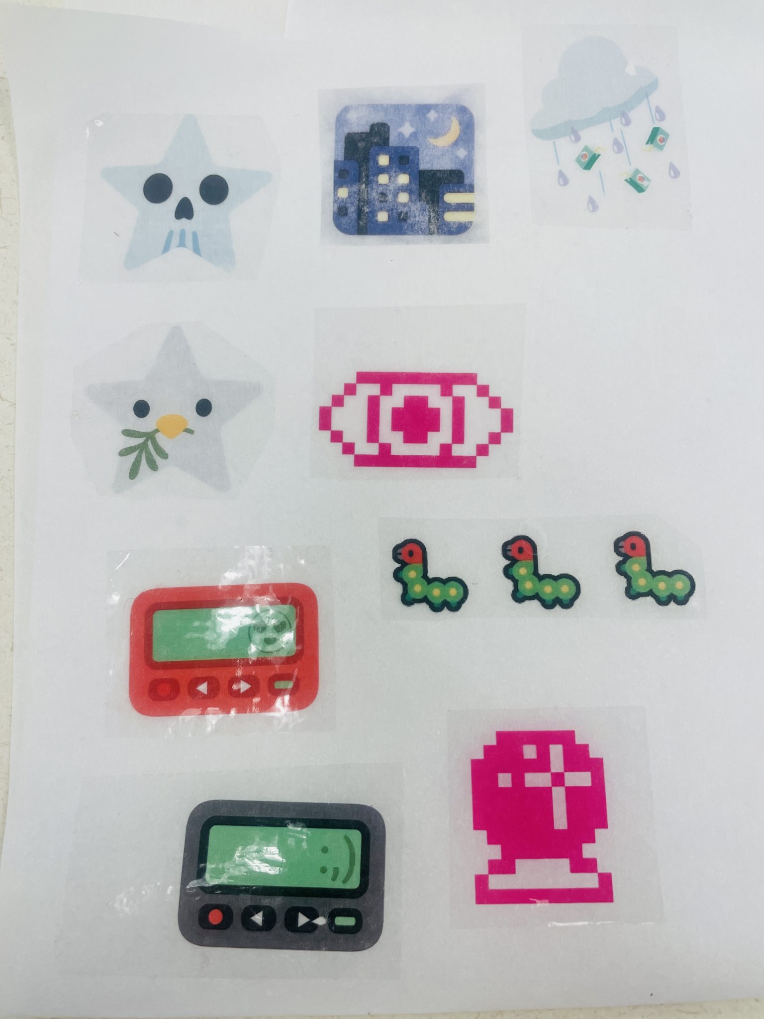 Image of a completed DIY sticker sheet, featuring nine shiny packing tape stickers arranged in a grid and made from emoji fusion and emojis sourced from emojipedia.org. 