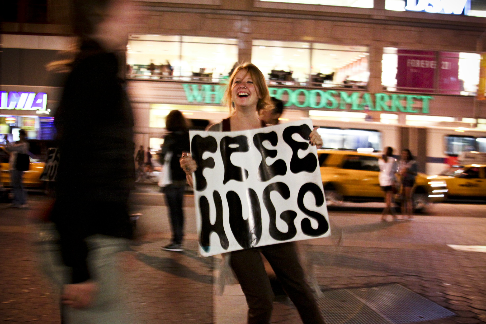 Photo of woman holding a sign that says "free hugs"