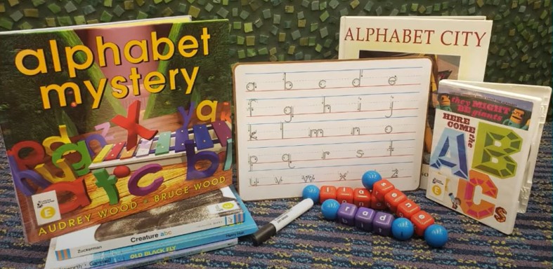 Contents of Little Red Reading Bag E. Includes books, DVDs, a dry erase board with letters on it, and twist and turn letter makers. 
