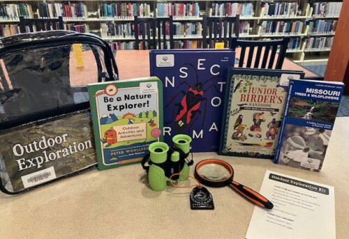 Display of contents of Outdoor Exploration Kit including backpack, books, binoculars, magnifying glass and compass