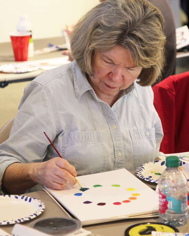 Woman focused on mixing and painting color swatches
