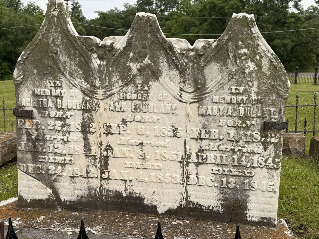 A weathered grave stone for three women