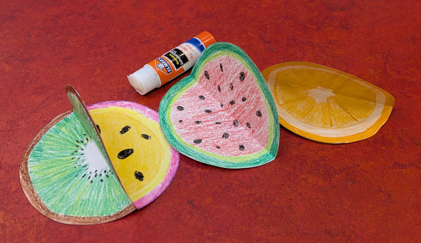 Circles folded in half, being glued together. 