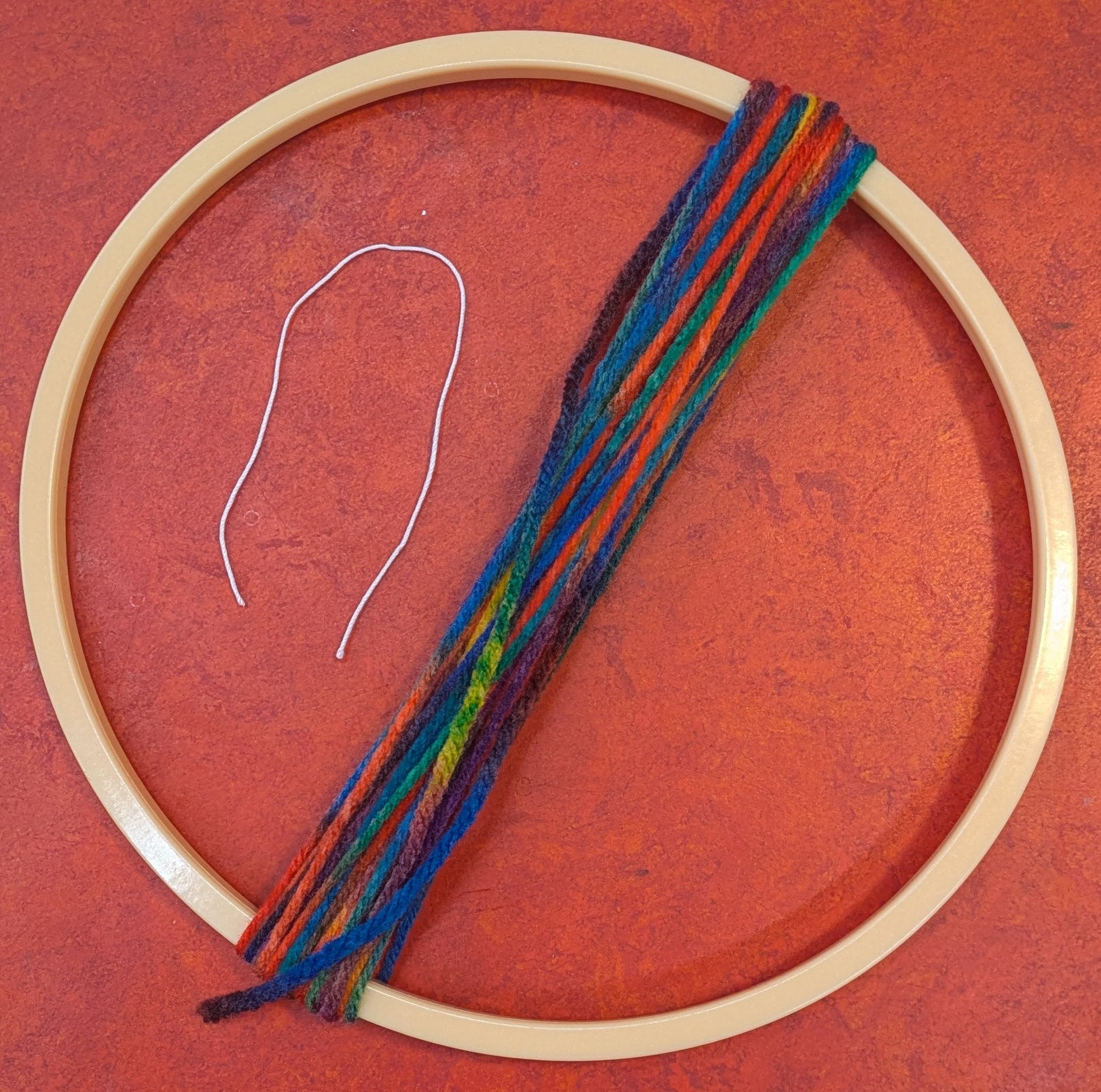 Yarn wrapped around embroidery hoop and a piece of thread