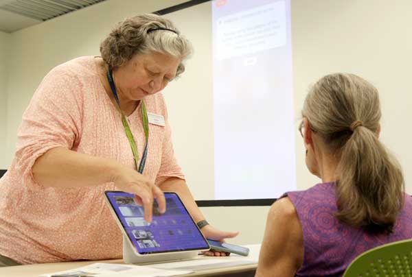 Library staff assisting a patron with a tablet