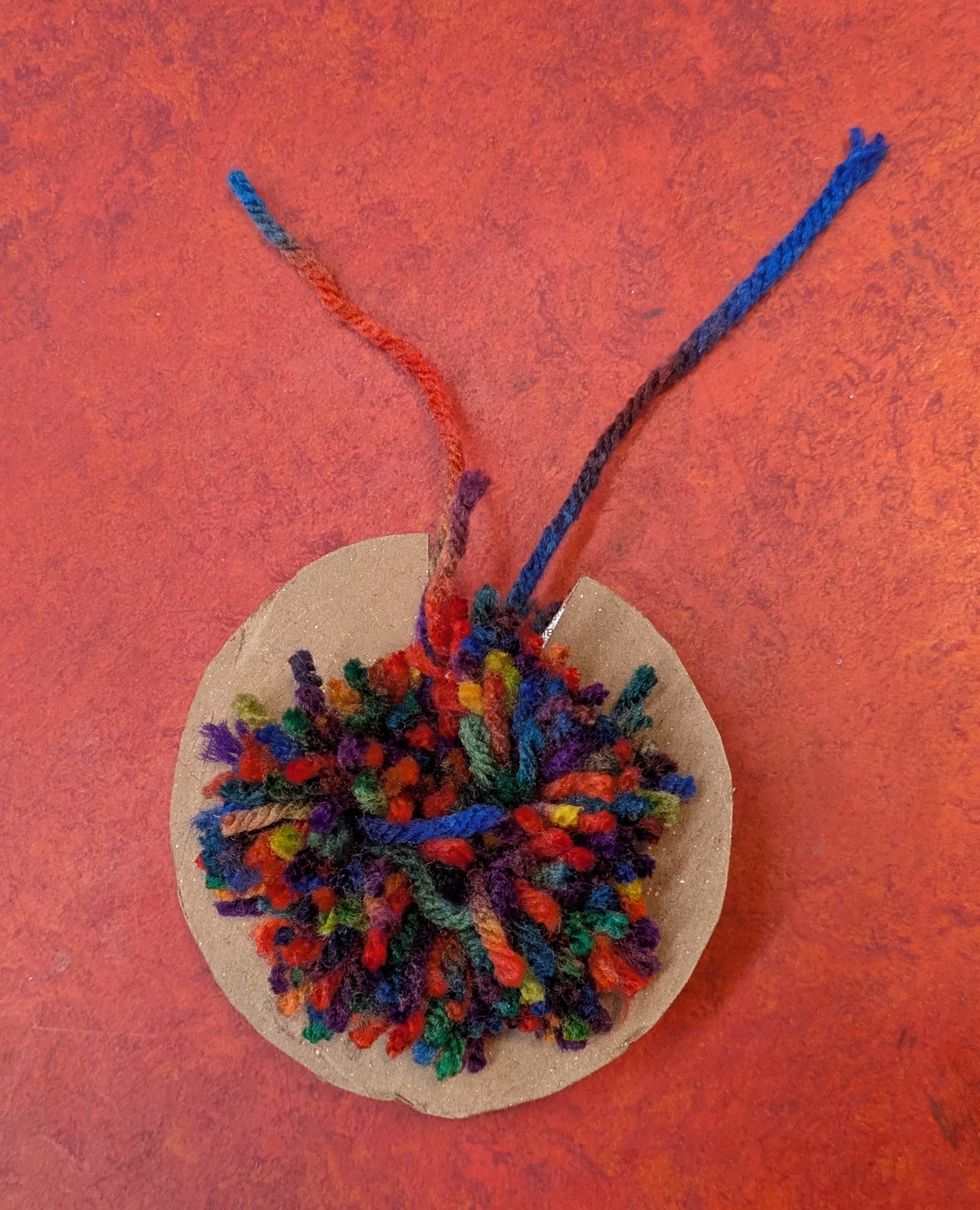 Nearly complete pom pom in the middle of cardboard 'c'
