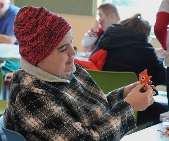 At a program for adults with disabilities, a person holds up a craft they are working on