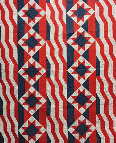 a quilt with stars and waving stripes in red, white and blue