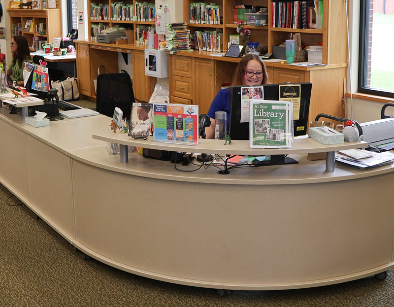 A staff member sits behind a long, low desk at the Ashland library